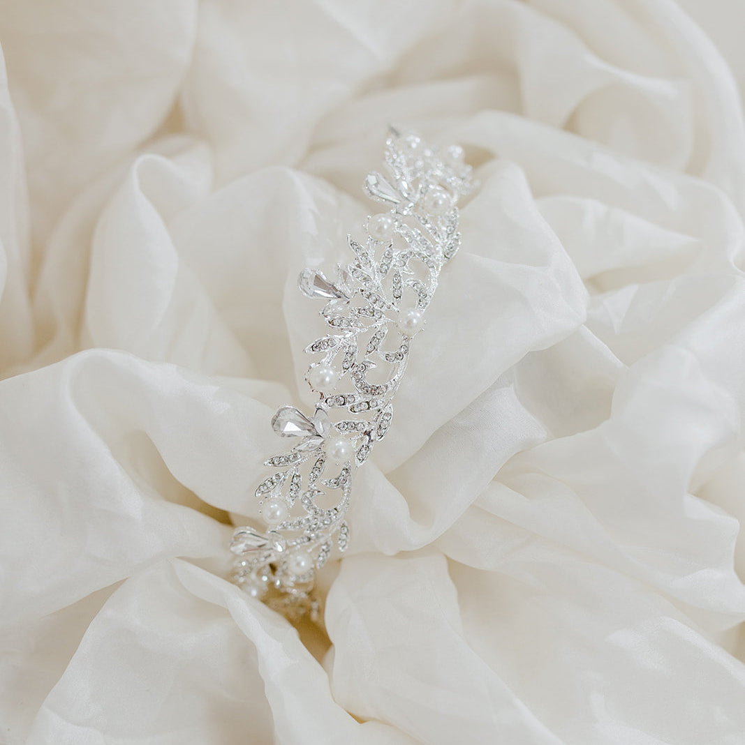 Decorative bridal hairpiece with crystals on a textured white fabric background