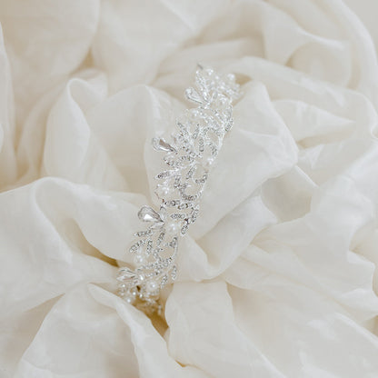 Decorative bridal hairpiece with crystals on a textured white fabric background