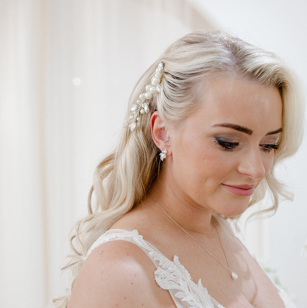 Pearl and crystal bridal hair comb nestled into soft blonde waves, featuring clustered ivory pearls and clear bead detailing for an elegant, organic finish.