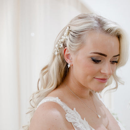 Pearl and crystal bridal hair comb nestled into soft blonde waves, featuring clustered ivory pearls and clear bead detailing for an elegant, organic finish.