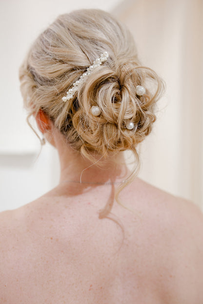 Bridal hair updo with decorative hairpiece against a neutral background